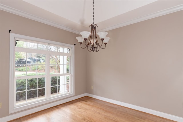 spare room featuring light hardwood / wood-style flooring, ornamental molding, and an inviting chandelier