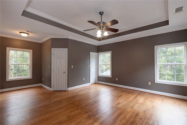 spare room featuring ceiling fan, light hardwood / wood-style floors, ornamental molding, and a tray ceiling