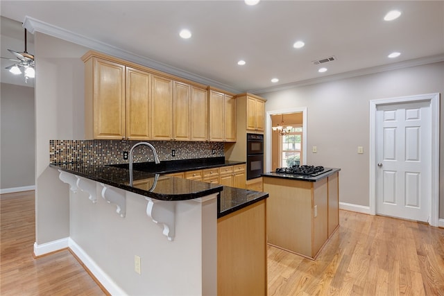 kitchen featuring crown molding, dark stone countertops, a kitchen island, kitchen peninsula, and stainless steel gas cooktop