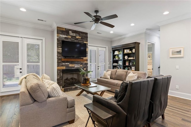 living room featuring a stone fireplace, french doors, wood-type flooring, and ornamental molding