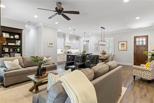 living room featuring crown molding, sink, ceiling fan with notable chandelier, and hardwood / wood-style flooring