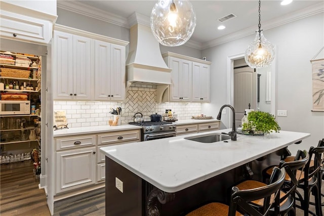 kitchen featuring custom exhaust hood, a breakfast bar, high end stainless steel range oven, sink, and white cabinetry