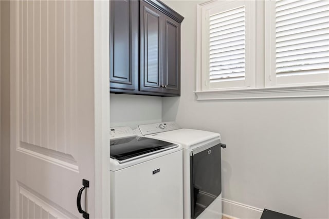 clothes washing area featuring cabinets and washer and clothes dryer