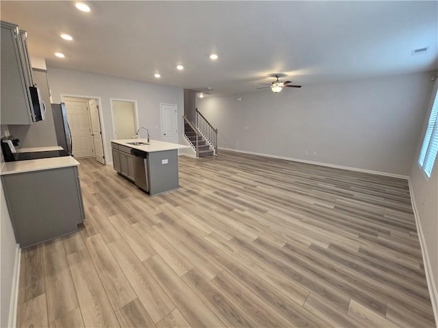 kitchen with light countertops, light wood-style flooring, dishwasher, a ceiling fan, and a sink