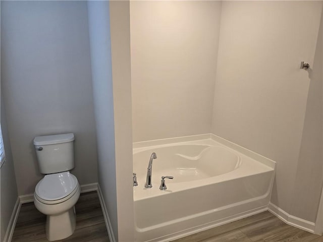 full bathroom featuring toilet, wood finished floors, baseboards, and a bath