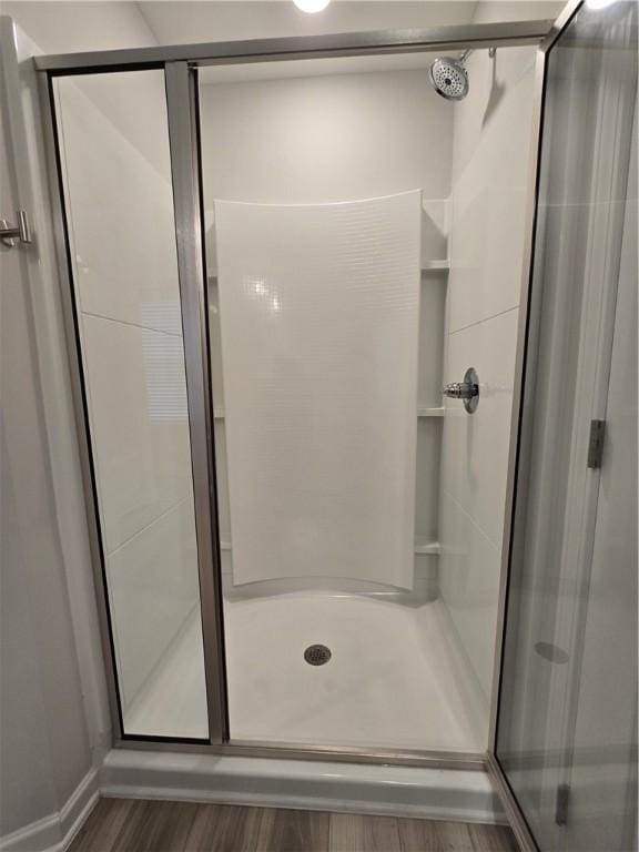 full bathroom with a stall shower and wood finished floors