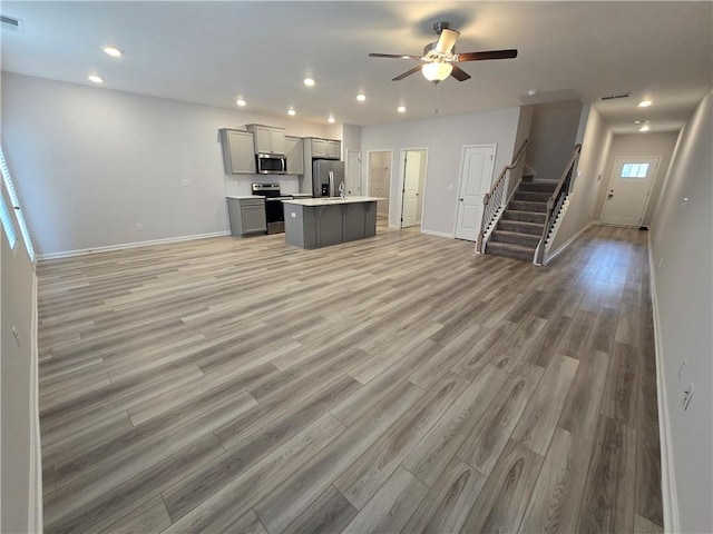kitchen with open floor plan, light countertops, stainless steel appliances, and gray cabinetry