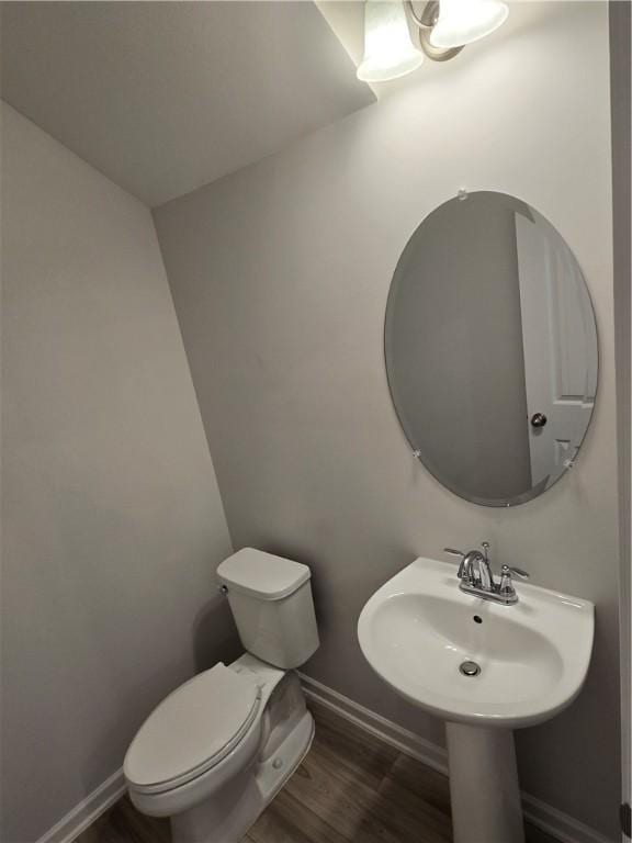 half bath featuring baseboards, toilet, and wood finished floors