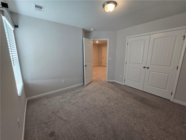 unfurnished bedroom featuring baseboards, visible vents, a closet, and carpet floors