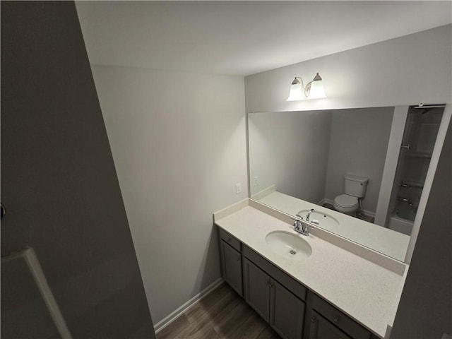 bathroom featuring baseboards, toilet, vanity, and wood finished floors