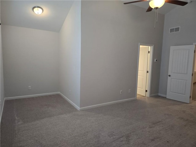 carpeted empty room with high vaulted ceiling, baseboards, ceiling fan, and visible vents