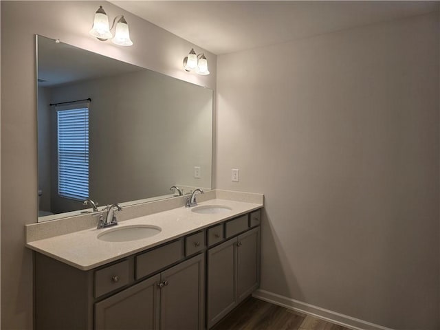 bathroom with baseboards, double vanity, a sink, and wood finished floors