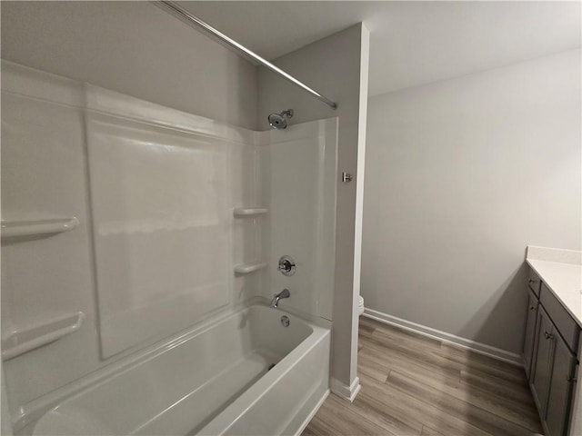 full bathroom with washtub / shower combination, baseboards, wood finished floors, toilet, and vanity