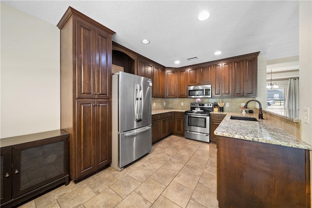 2107 Rockledge Cir, Opelika, AL 36801 - kitchen with stainless steel appliances, a sink, decorative backsplash, light stone counters, and a peninsula