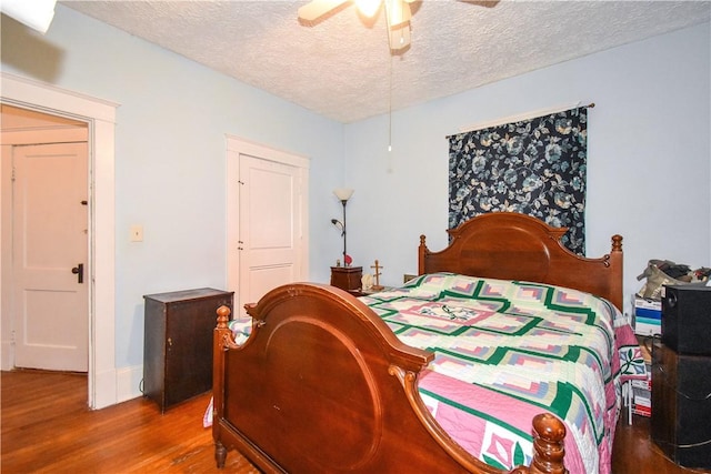 bedroom featuring a textured ceiling, wood finished floors, and a ceiling fan