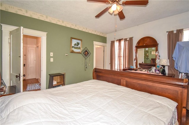 bedroom with multiple windows, a ceiling fan, and a textured ceiling