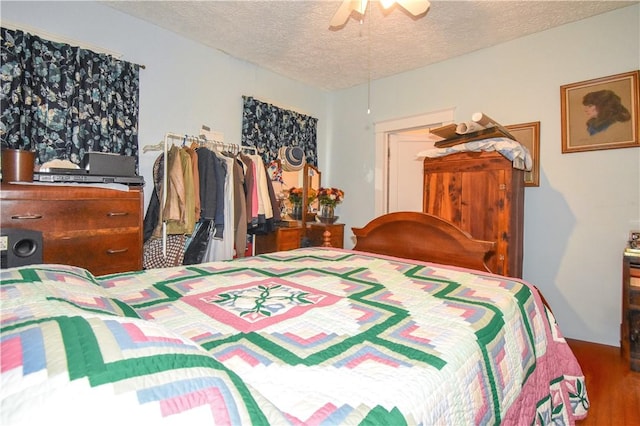 bedroom featuring ceiling fan, wood finished floors, and a textured ceiling