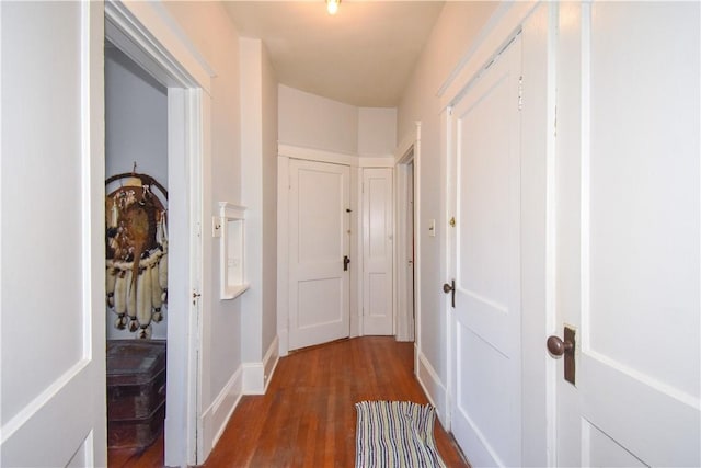 hallway featuring baseboards and dark wood-style flooring