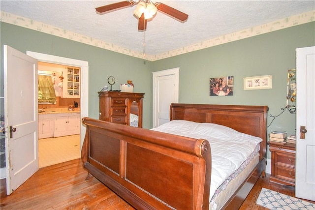 bedroom featuring connected bathroom, a textured ceiling, a ceiling fan, and wood finished floors