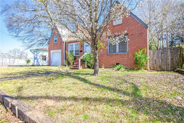 view of front of property with brick siding, a garage, a front lawn, and fence