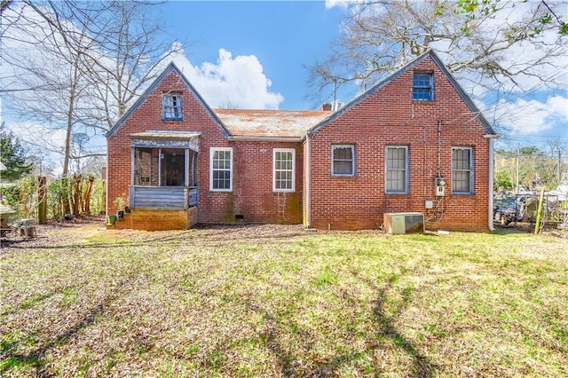 back of house with brick siding, central AC unit, and a yard