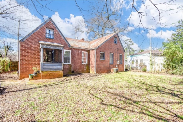 view of front of home featuring central air condition unit, brick siding, and a front yard