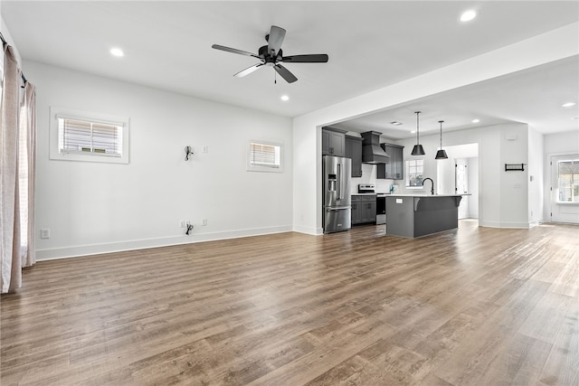 unfurnished living room featuring dark wood-type flooring, plenty of natural light, and ceiling fan