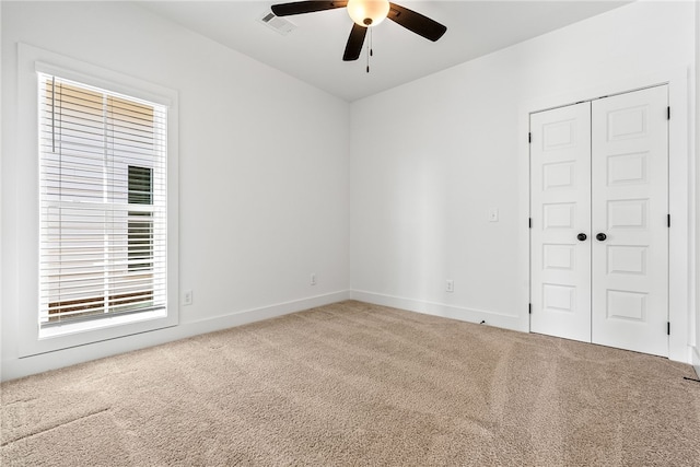 carpeted empty room featuring a wealth of natural light and ceiling fan