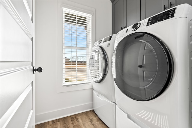 clothes washing area featuring hardwood / wood-style flooring, cabinets, and separate washer and dryer