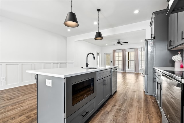 kitchen with sink, gray cabinetry, hanging light fixtures, appliances with stainless steel finishes, and a kitchen island with sink