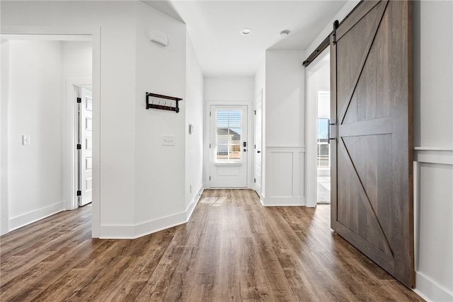 hall with wood-type flooring and a barn door