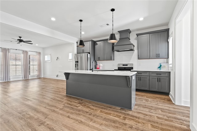 kitchen with pendant lighting, sink, gray cabinets, stainless steel appliances, and custom range hood