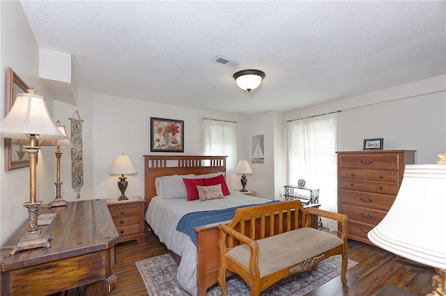 bedroom featuring visible vents, dark wood finished floors, and a textured ceiling