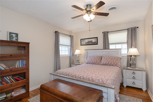 bedroom with dark wood-style flooring, visible vents, and multiple windows