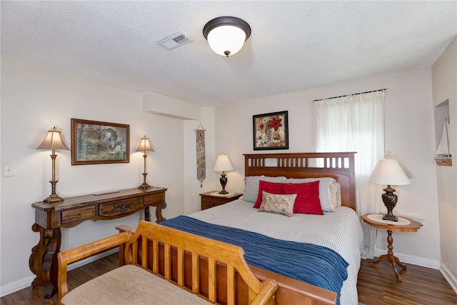 bedroom featuring visible vents, a textured ceiling, baseboards, and wood finished floors