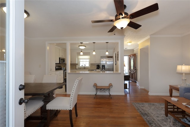 dining area featuring ornamental molding, dark wood-type flooring, a ceiling fan, and baseboards