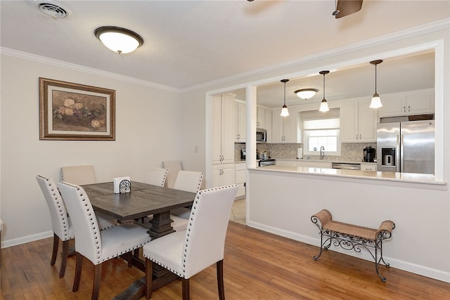 dining area with ornamental molding, wood finished floors, visible vents, and baseboards