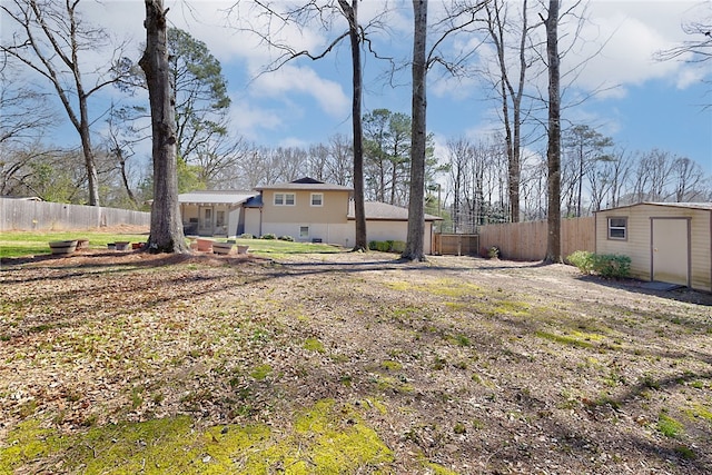 view of yard featuring an outbuilding, a shed, and fence