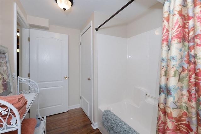 bathroom with wood finished floors and shower / tub combo with curtain