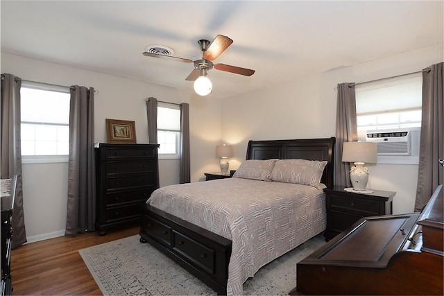 bedroom featuring baseboards, visible vents, ceiling fan, wood finished floors, and cooling unit