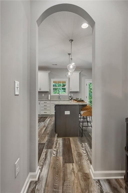223 Meadowlark Dr, Smiths Station, AL 36877 - kitchen featuring dark wood-style floors, white cabinetry, arched walkways, a breakfast bar area, and baseboards