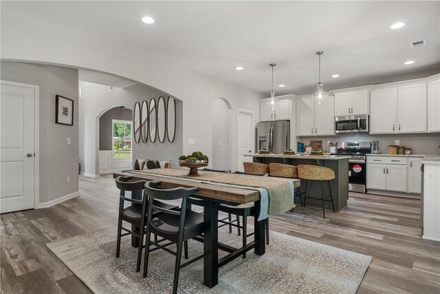 223 Meadowlark Dr, Smiths Station, AL 36877 - dining space with arched walkways, visible vents, and light wood-style floors