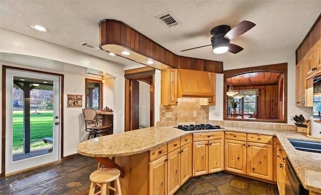 kitchen featuring ceiling fan, tasteful backsplash, kitchen peninsula, a breakfast bar, and appliances with stainless steel finishes