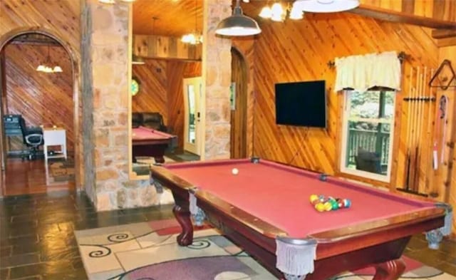 recreation room with wood walls and billiards