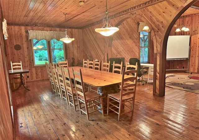 dining room featuring wood-type flooring, wood ceiling, and wooden walls