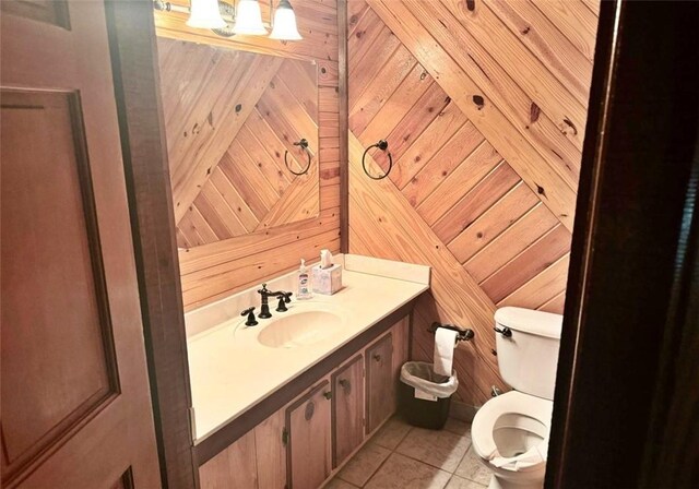 bathroom featuring tile patterned flooring, vanity, toilet, and wooden walls