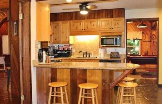 kitchen with ceiling fan, a kitchen bar, kitchen peninsula, and sink