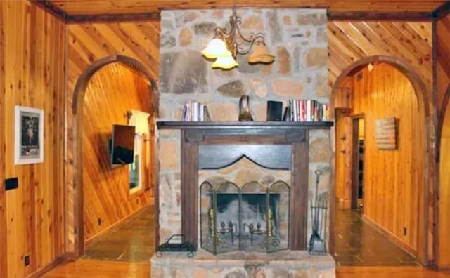 room details with hardwood / wood-style flooring, wood walls, and a stone fireplace