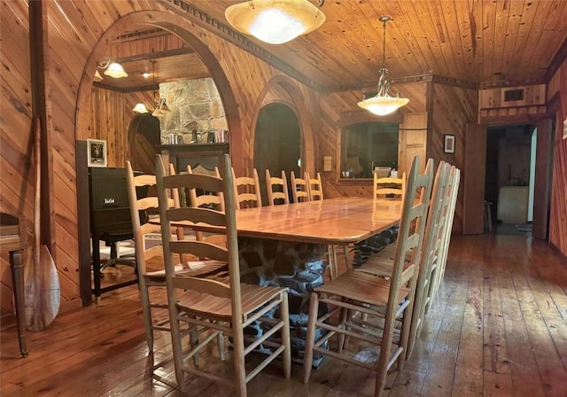 dining area with wood walls, dark wood-type flooring, and wood ceiling