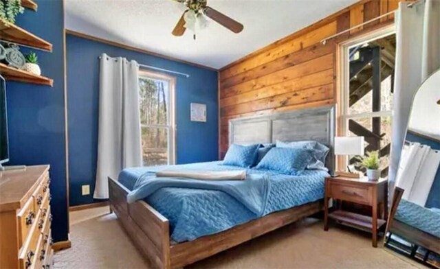 carpeted bedroom with ceiling fan and wooden walls